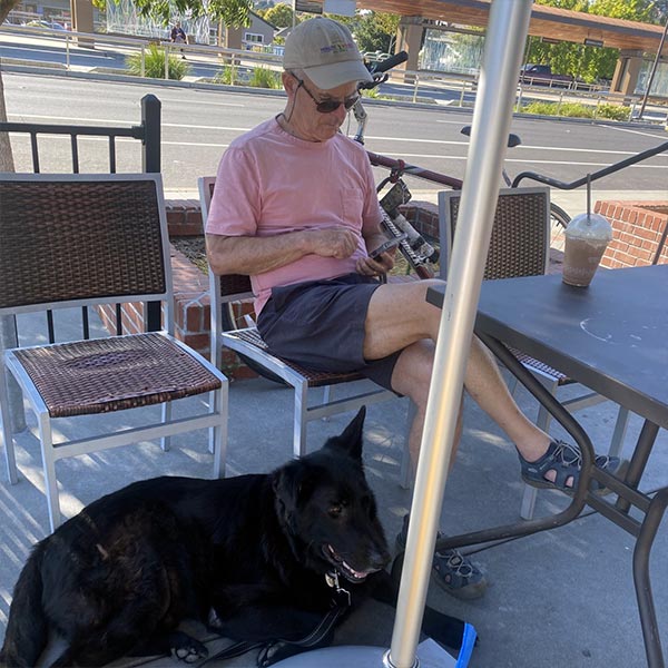 Beau the dog relaxing with his owner at a sidewalk cafe