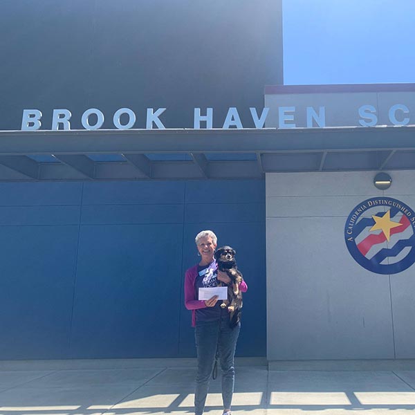 Priscilla Locke receives a generous donation from Brook Haven School with her dog Harvey